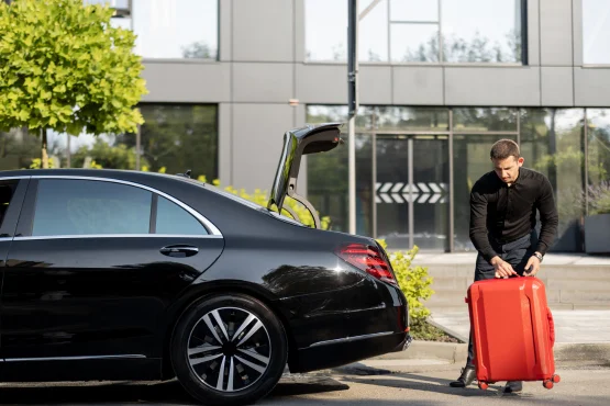 chauffeur taxi medoc chargant une valise dans son coffre avant arrivee cliente